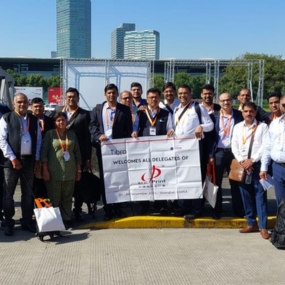 Group of delegates posing outdoors with a banner