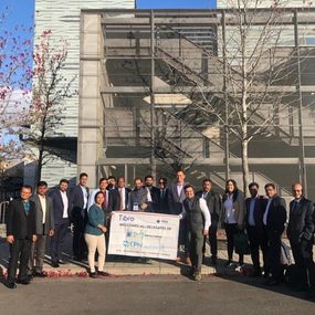 A group of professionals posing outdoors with a banner.