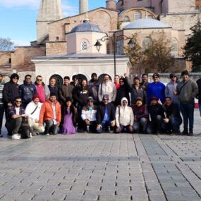 Group posing in front of a historic building with domes and minarets