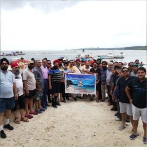 Group posing on a beach with boats and ocean in the background.