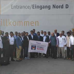 A large group of professionals posing with a 'Tibro' banner