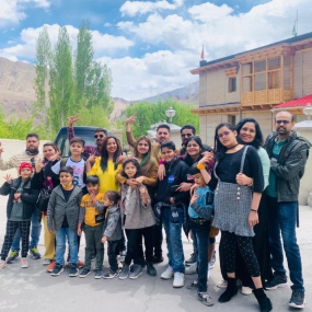 A cheerful family group posing outdoors with mountains in the background.