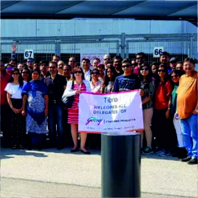 A group of people posing with a welcome banner outdoors.
