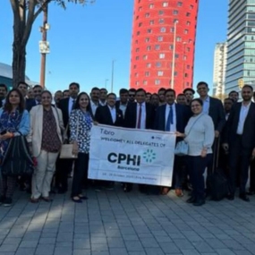 A large group of professionals holding a banner at CPHI event.