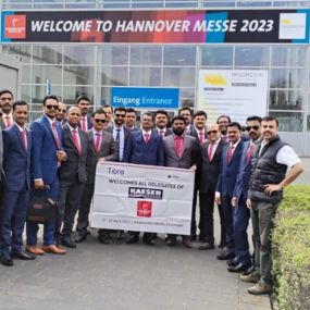 A group of professionals posing with a banner at Hannover Messe 2023.