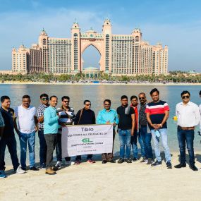 Group posing with a banner on a beach near Atlantis, Dubai.