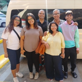 A group of six people posing together in front of a white vehicle