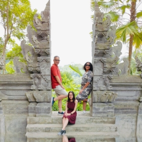 Three people posing at an ornate stone gateway with intricate carvings