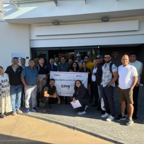 Group posing outside a building holding a CPHI event banner.