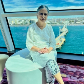 An elderly woman sitting indoors by a large window