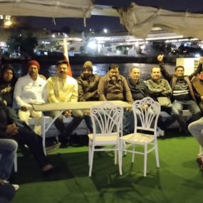 Group of people sitting on a boat with city lights in the background.