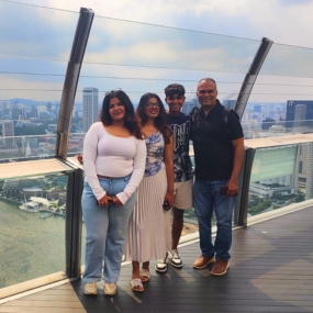 Family posing on a high-rise observation deck with city skyline.